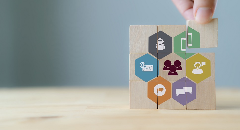A hand stacking wooden blocks with icons symbolizing various aspects of personalized customer service, like email, groups, service, and time management.