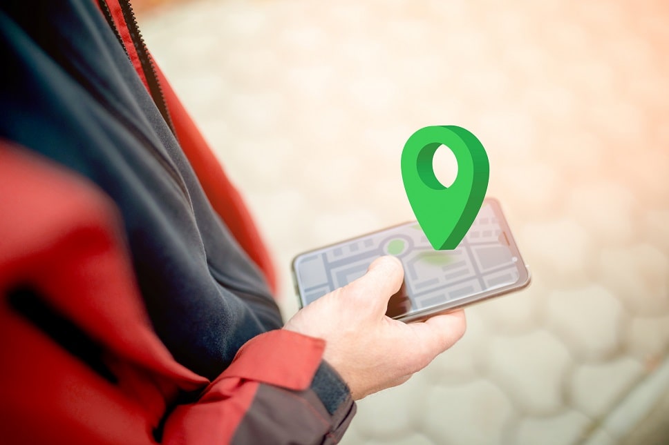 Person using a smartphone with a map application and a large green location pin overlay, symbolizing GPS navigation.