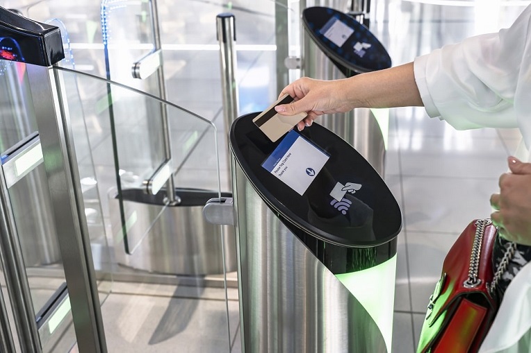 Person using a contactless card at a security turnstile, representing modern access control and payment systems.