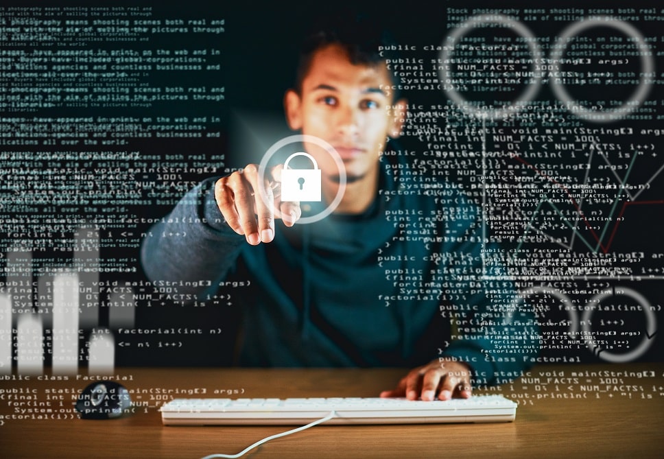 Man at computer reaching towards screen with a digital padlock symbol, representing cybersecurity and data protection using the Sitefinity CMS.